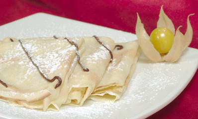 Pancakes (Crepes) with chocolate, sugar and a physalis fruit
