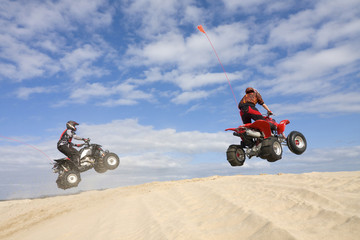 Two Quads jumping sand dunes
