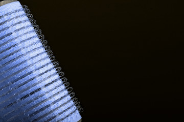 Blue hair curler against black background
