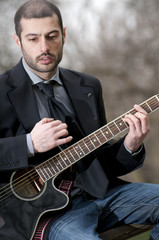 ragazzo in giacca suona la chitarra