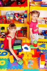 Child with puzzle, block and construction set in play room.