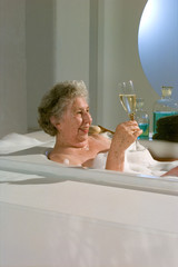 Oma in der Badewanne trinkt Champagner