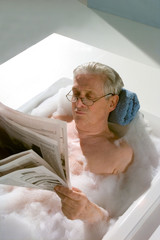 Baden, Opa in der Badewanne liest Zeitung