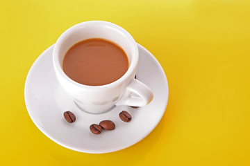 Small white cup of coffee with coffee grain on yellow background