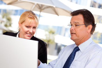 Businessman and Female Colleague Using Loptop Outdoors