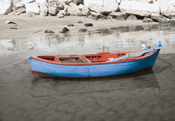 Fishing boat moored on shore of sandy beach.