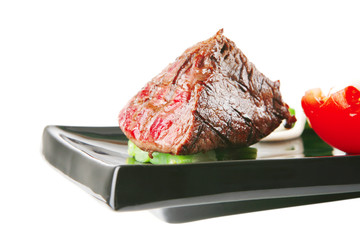 fillet mignon on a black plate with tomato