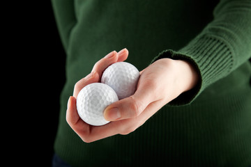 closeup shot of a female hand holding two golf balls