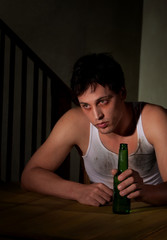 Depressed young man with beer bottle