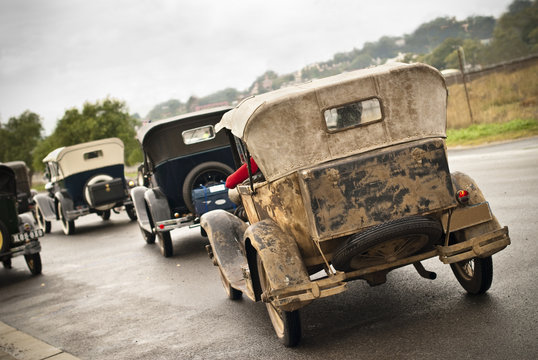 Convoy of old 1930's cars in rain