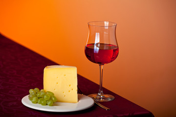 Stück Käse, eine Traube und Rotwein