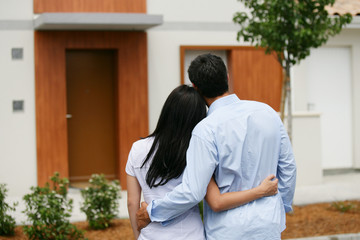 Couple debout de dos devant une maison