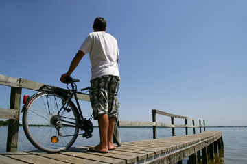 Homme debout sur un ponton avec un vélo