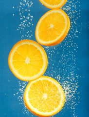Fresh orange dropped into water with bubbles