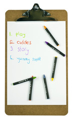 Clipboard with a childs to-do list and colorful crayons