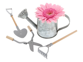 Gießkanne mit Gerbera und Gartengeräte