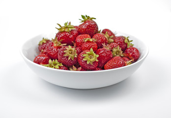 A white plate full of strawberries on white background.