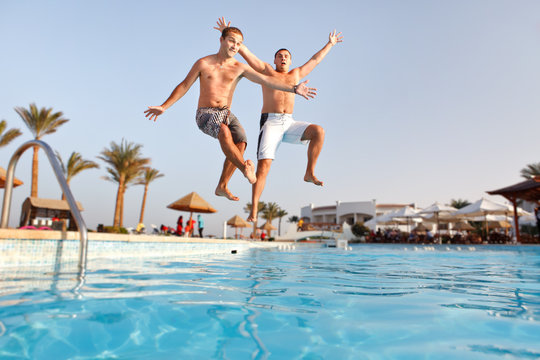 Two men jumping in swimming pool together
