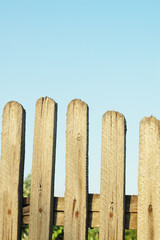 Old wooden picket fence against blue sky
