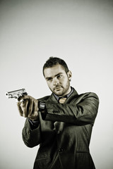 Fototapeta na wymiar Dressed man pointing a gun he holds in his hands