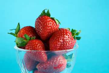 Strawberry in glass container on blue background