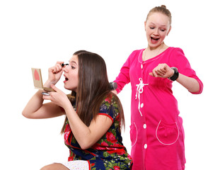 Two young girlfriends do a make-up and look at the watch