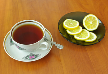 Cup of tea and slices of lemon on plate