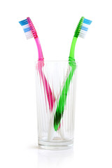 Two colorful tooth-brushes inside a glass
