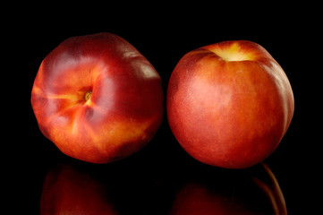Two red nectarine peaches isolated on black background