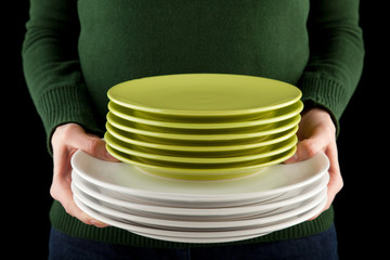 hands holding a pile of green and white dishes