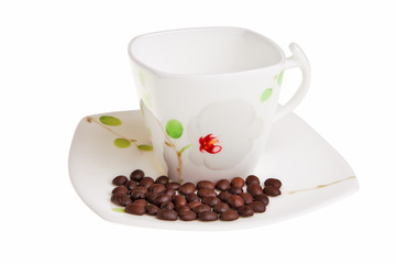 White cup with coffee beans on saucer.