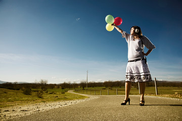 Fototapeta na wymiar woman with balloons and headphones on a blue sky summer day