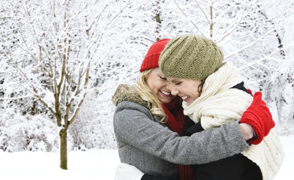 Two Girl Friends Hugging Outside In Winter