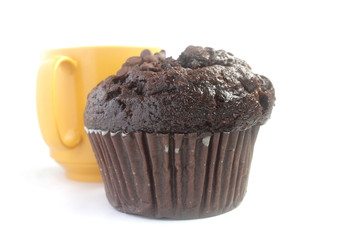 Chocolate muffin and a yellow cup isolated on white background