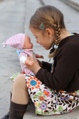 Pretty young girl cuddles and plays with her doll. © wazymodo