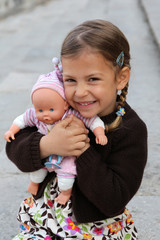 A pretty young girl cuddles and plays with her doll