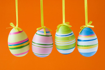 four colorful easter eggs isolated on orange background
