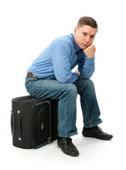 pensive young man sitting on a hand bag