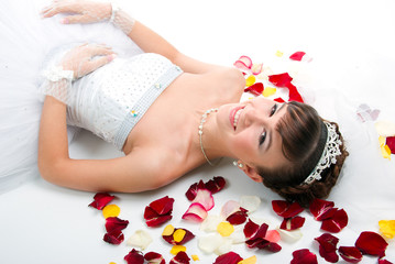 Obraz na płótnie Canvas Beautiful bride on floor among red rose petals
