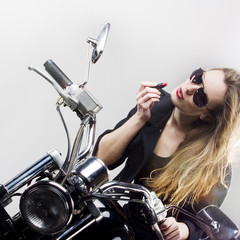 Obraz na płótnie Canvas Rock'n'roll girl, The girl paints lips sitting on a motorbike