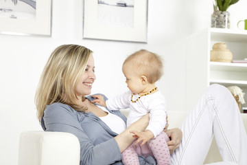 junge mutter mit baby auf weißem sofa