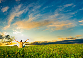Fototapeta na wymiar man sitting in the field under sunset