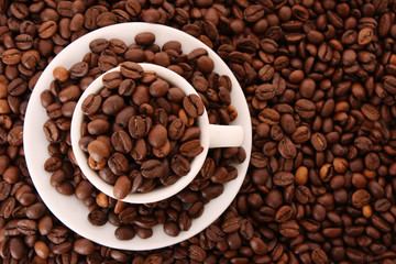 Small white cup of coffee with coffee grain on grain background