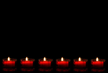 Lit red candles as a bottom border on a black background.
