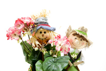 Strohpuppe hinter Blumen