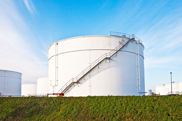 white tanks for petrol and oil in tank farm with blue sky