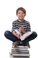 Junge sitzt auf Büchern und liest