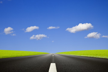 Empty black roadway against a deep blue sky