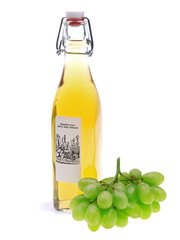 eine Flasche Weißweinessig mit einem Bündel frischer grüner Trauben auf weißem Hintergrund