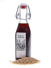 flasche sesamöl mit sesamsaate auf weißem hintergrund 	